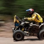An image featuring a rugged ATV rider cruising through the picturesque trails of Massachusetts, surrounded by lush forests and vibrant autumn foliage