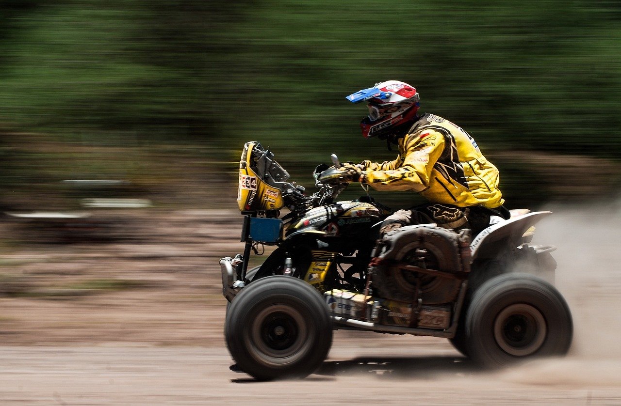 An image featuring a rugged ATV rider cruising through the picturesque trails of Massachusetts, surrounded by lush forests and vibrant autumn foliage