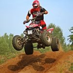 An image showcasing a rugged ATV rider navigating through the picturesque Minnesota wilderness