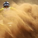 An image showcasing a wide expanse of red desert terrain in Utah, with an ATV rider clad in protective gear effortlessly maneuvering through rocky trails, highlighting the thrilling adventure of ATV and UTV exploration
