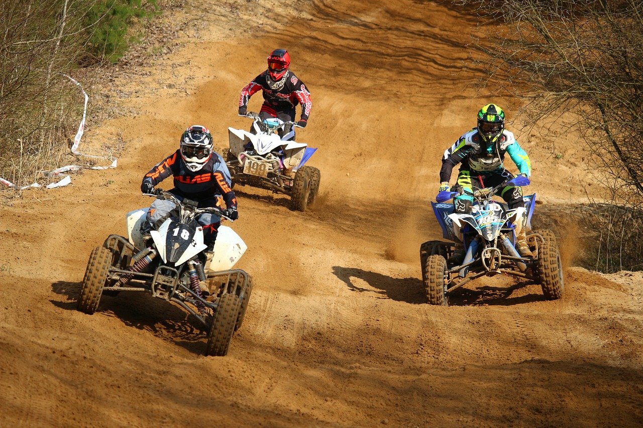 An image that showcases the vibrant Hawaiian landscape with an ATV rider navigating through lush forests, passing by a clear blue stream with majestic mountains in the background