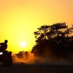 An image showcasing an expansive North Dakota landscape with an ATV and UTV prominently featured, traversing through scenic trails, highlighting the diverse terrain and emphasizing the importance of understanding local laws