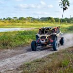 An image showcasing a rugged terrain with a UTV in motion, driven by an adventurous individual