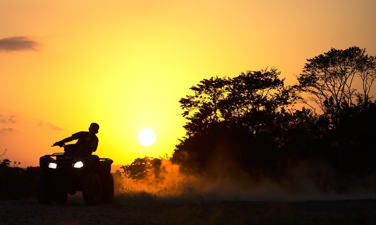 An image showcasing an ATV MAN standing next to a lineup of different-sized ATVs, offering a clear visual comparison of sizes